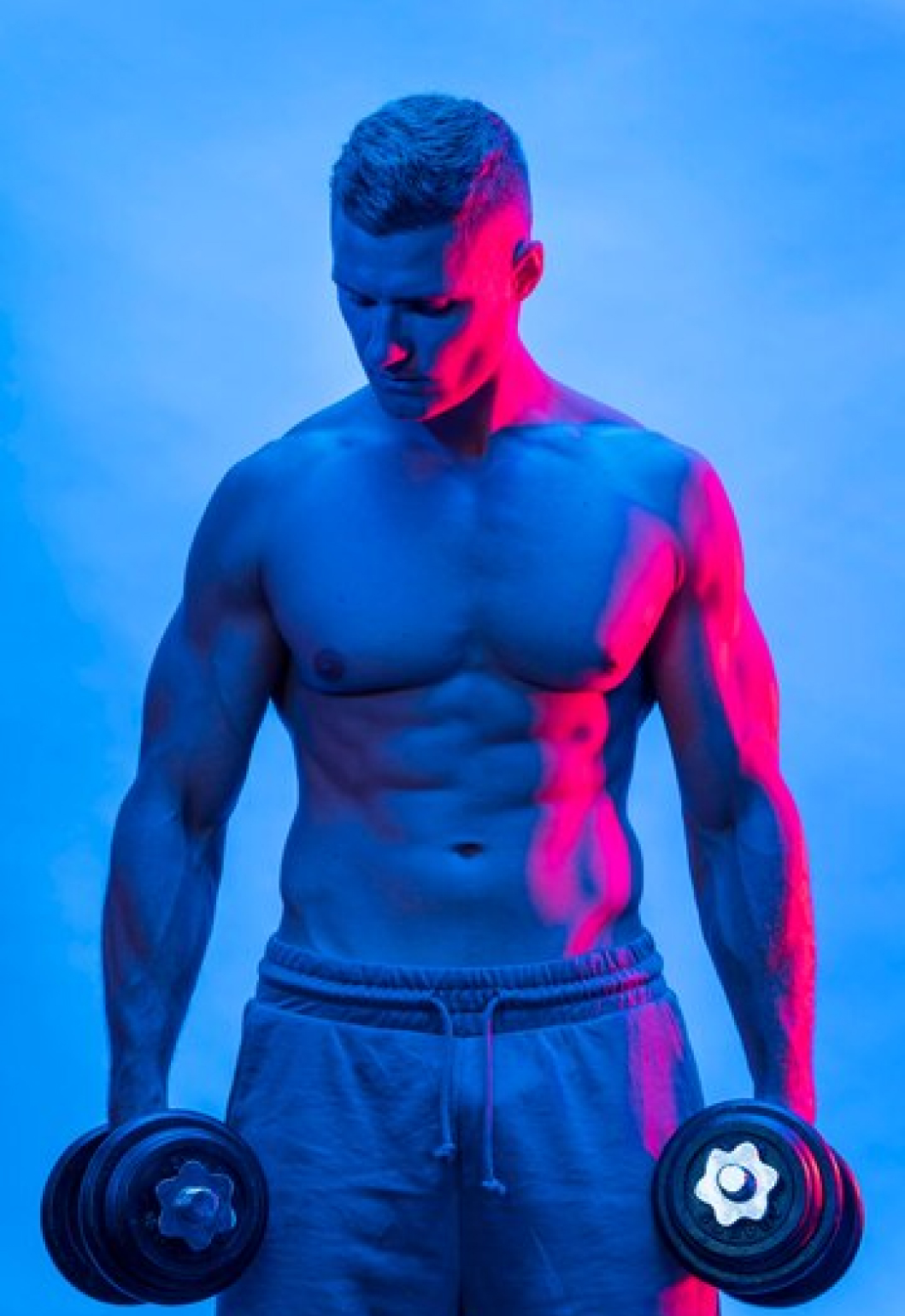Мужчина со спортивным телосложением с гантелями в руках